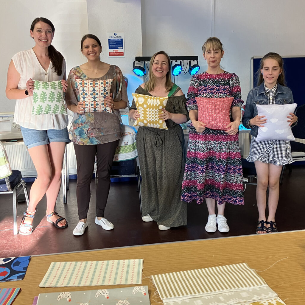 Adults and children showing what they have made at sewing classes in Tameside, Manchester