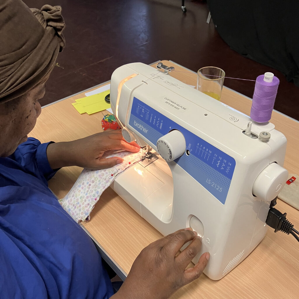 An adult at a sewing machine at her beginner's sewing lesson