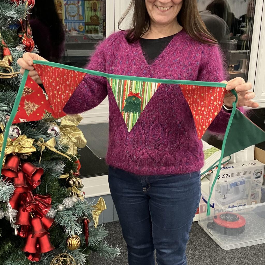 An adult showing what she has made at a Christmas Bunting Sewing Workshop