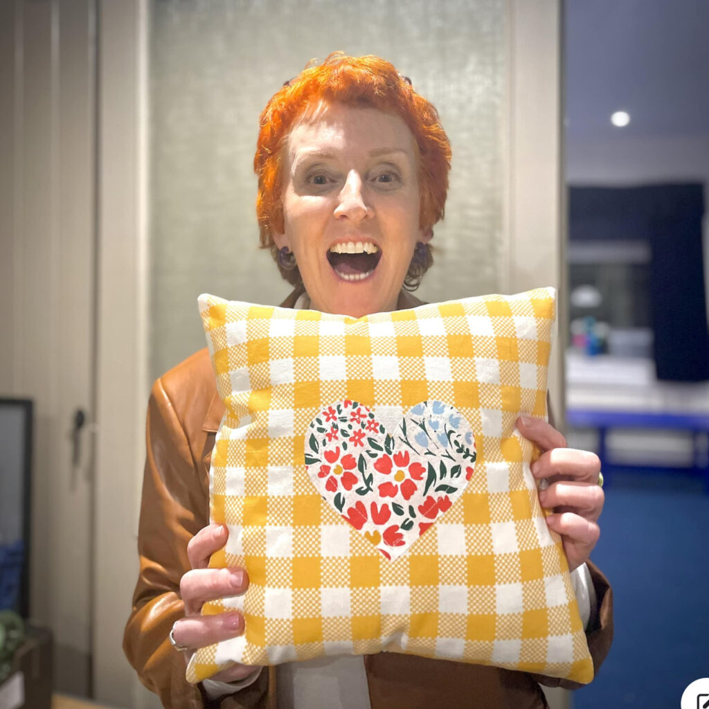 An adult showing a cushion made at a sewing class in Tameside
